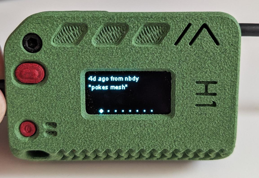 Photo of my meshtastic device, 3d printed green case, screen on with a message from 4 days ago of a user nbdy saying “pokes mesh”